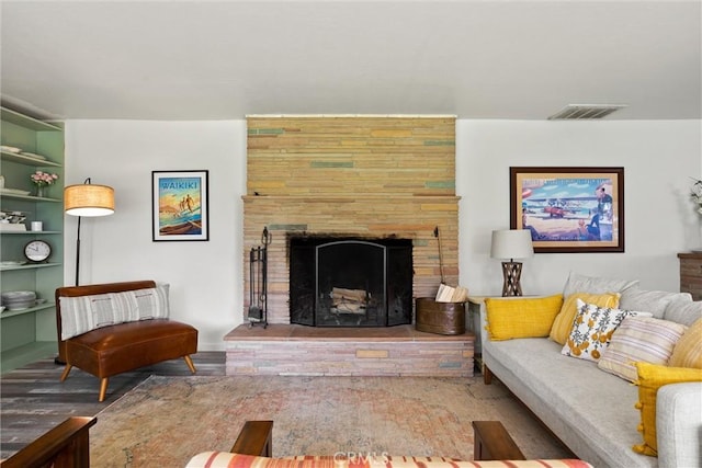 living room featuring wood finished floors, a large fireplace, and visible vents