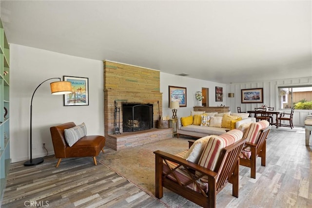 living room featuring light wood-style flooring, visible vents, and a fireplace