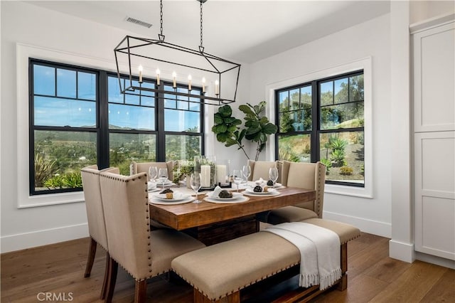 dining space featuring wood finished floors, plenty of natural light, a chandelier, and visible vents