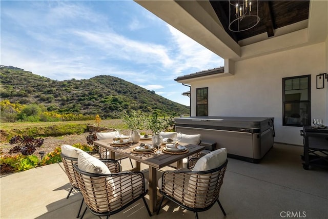 view of patio / terrace featuring a hot tub, a mountain view, and outdoor dining space
