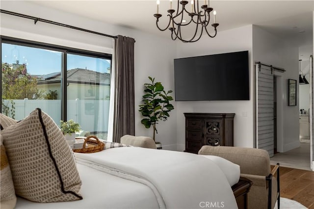 bedroom with access to outside, a barn door, wood finished floors, and a notable chandelier
