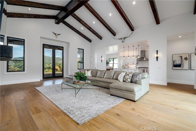 living area featuring high vaulted ceiling, french doors, light wood-style floors, and beam ceiling