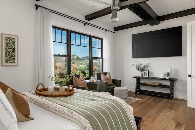 bedroom with a ceiling fan, baseboards, beamed ceiling, and wood finished floors