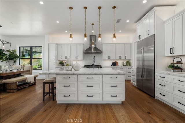 kitchen featuring stainless steel built in fridge, visible vents, wall chimney exhaust hood, and dark wood finished floors