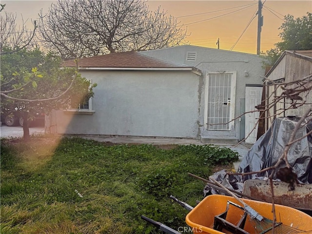 property exterior at dusk featuring stucco siding