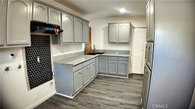 kitchen with a sink, dark wood-style flooring, light countertops, freestanding refrigerator, and gray cabinets