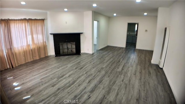 unfurnished living room featuring wood finished floors, a fireplace, baseboards, and recessed lighting