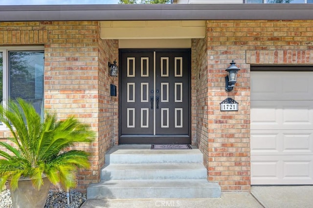 doorway to property featuring a garage and brick siding