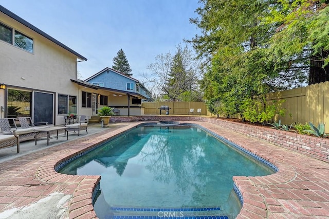 view of pool with a pool with connected hot tub, a patio, and a fenced backyard
