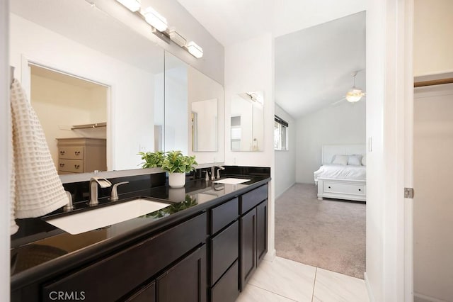 ensuite bathroom with double vanity, a ceiling fan, vaulted ceiling, and a sink