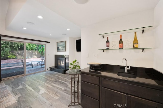 bar featuring recessed lighting, light wood finished floors, wet bar, and a sink