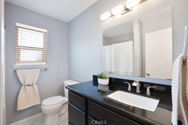 bathroom featuring toilet, vanity, and baseboards