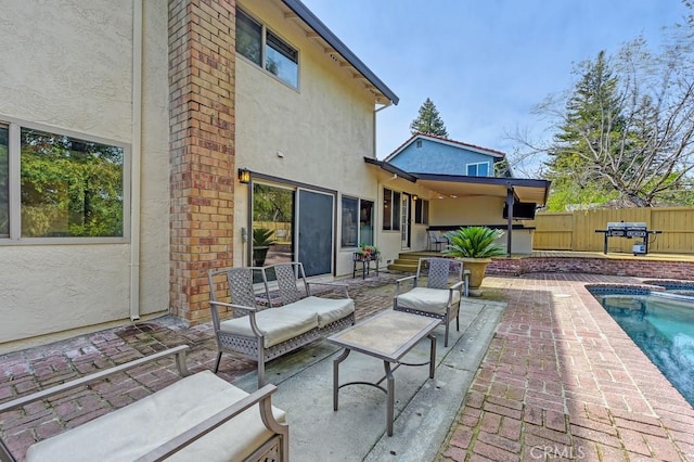 rear view of property featuring stucco siding, fence, and a patio area
