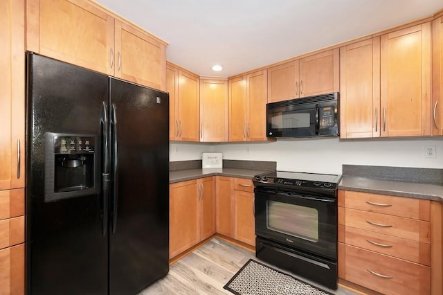 kitchen with black appliances, light wood finished floors, dark countertops, and light brown cabinetry