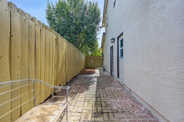 view of property exterior with a patio, stucco siding, a gate, and fence