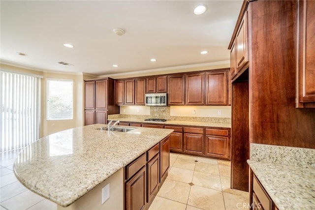 36368 Par Ln, Beaumont, CA 92223 - kitchen featuring appliances with stainless steel finishes, ornamental molding, a sink, light stone counters, and a kitchen island with sink