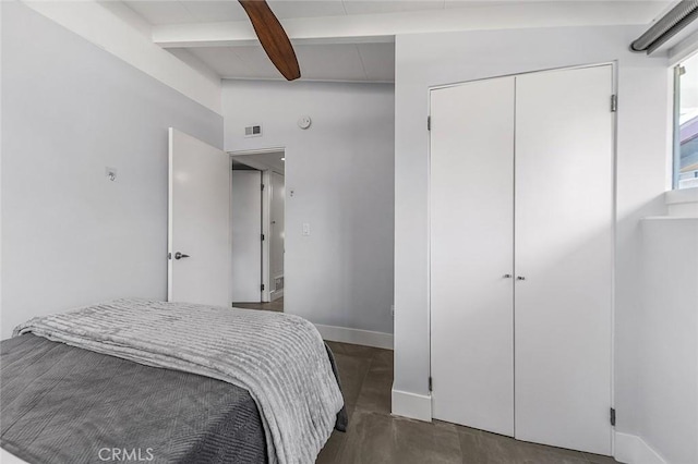 bedroom featuring beamed ceiling, a closet, visible vents, baseboards, and wood finished floors
