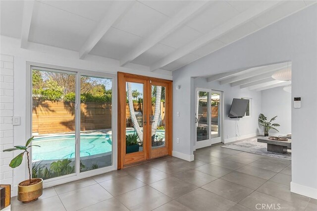 doorway to outside with baseboards, vaulted ceiling with beams, a healthy amount of sunlight, and tile patterned flooring