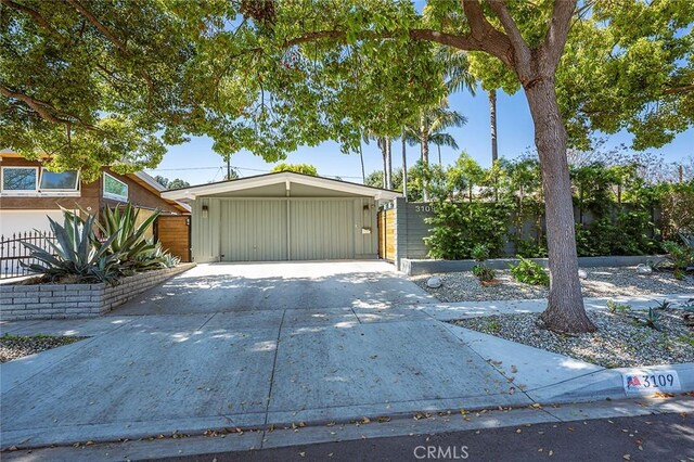 mid-century home with concrete driveway, an attached carport, and fence