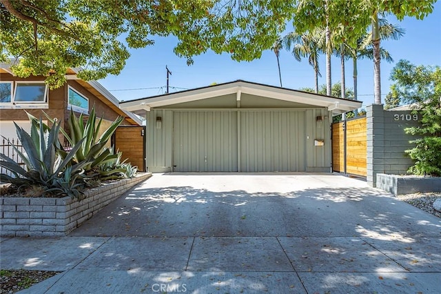 garage with fence, a carport, and driveway