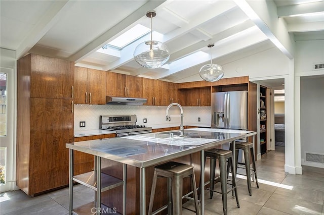 3109 Pattiz Ave, Long Beach, CA 90808 - kitchen featuring stainless steel appliances, under cabinet range hood, tasteful backsplash, a skylight, and a kitchen bar
