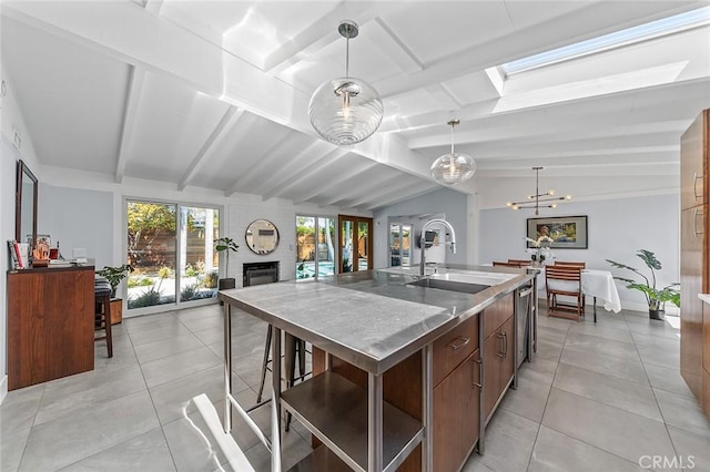 kitchen with stainless steel counters, a sink, vaulted ceiling with skylight, and a healthy amount of sunlight