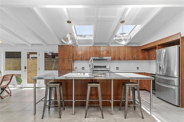 kitchen featuring stainless steel fridge, under cabinet range hood, light countertops, backsplash, and a sink