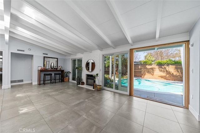 unfurnished living room featuring a large fireplace, visible vents, baseboards, tile patterned floors, and vaulted ceiling with beams