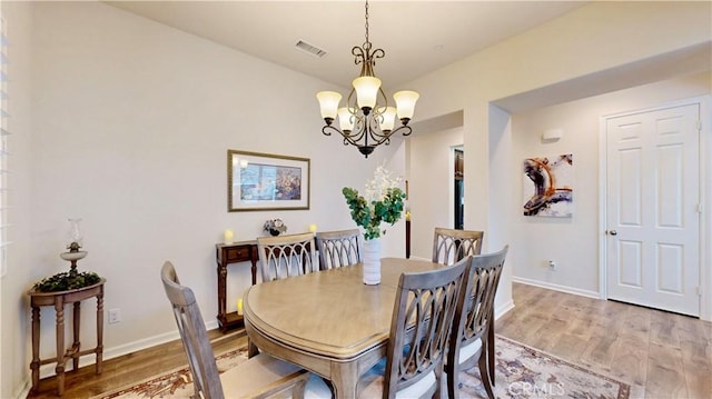 dining area with baseboards, visible vents, a notable chandelier, and light wood finished floors