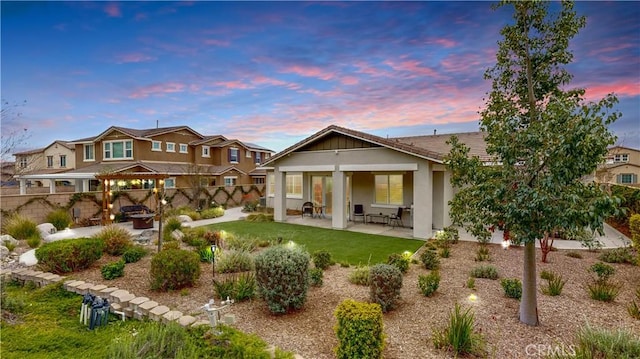 back of house featuring stucco siding, a patio, an outdoor fire pit, fence private yard, and a yard