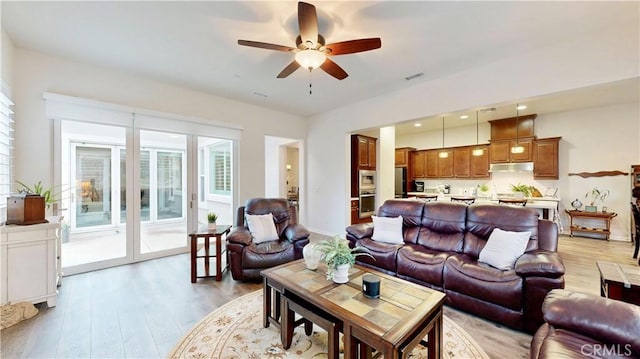 living room with visible vents, ceiling fan, and light wood-style flooring