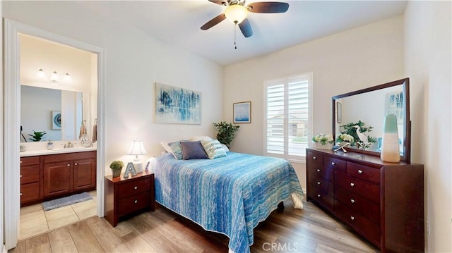bedroom with a sink, light wood-style flooring, ensuite bath, and a ceiling fan