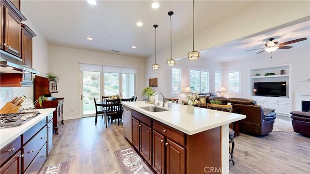kitchen featuring open floor plan, built in features, light countertops, a sink, and appliances with stainless steel finishes