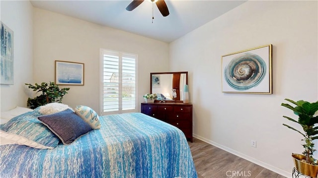 bedroom featuring baseboards, wood finished floors, and a ceiling fan