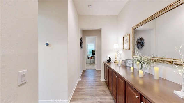 hall featuring light wood-style flooring and baseboards