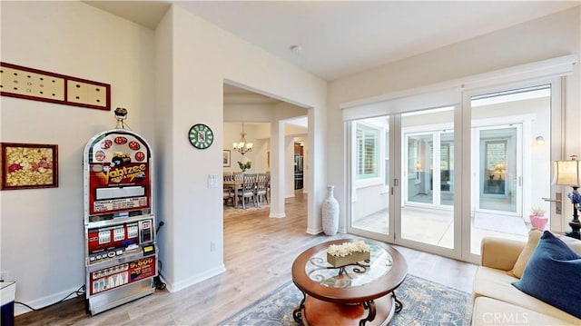 living area featuring baseboards, a notable chandelier, and wood finished floors
