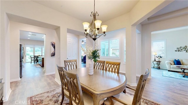 dining area with baseboards, light wood-style flooring, and a notable chandelier