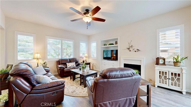 living room with plenty of natural light, built in features, ceiling fan, and wood finished floors
