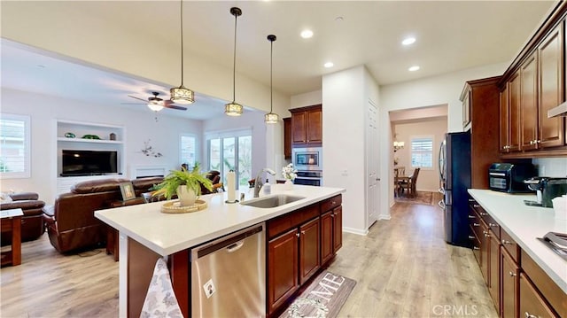 kitchen with light countertops, ceiling fan, appliances with stainless steel finishes, a sink, and open floor plan