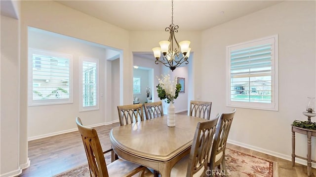 dining room featuring a wealth of natural light, a notable chandelier, baseboards, and wood finished floors