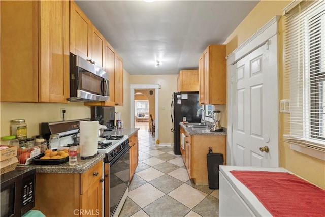 27 E Platt St, Long Beach, CA 90805 - kitchen featuring black appliances, a sink, light tile patterned floors, arched walkways, and dark countertops