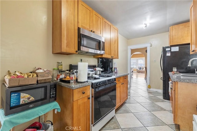 27 E Platt St, Long Beach, CA 90805 - kitchen featuring stainless steel microwave, range with gas stovetop, arched walkways, and light tile patterned floors