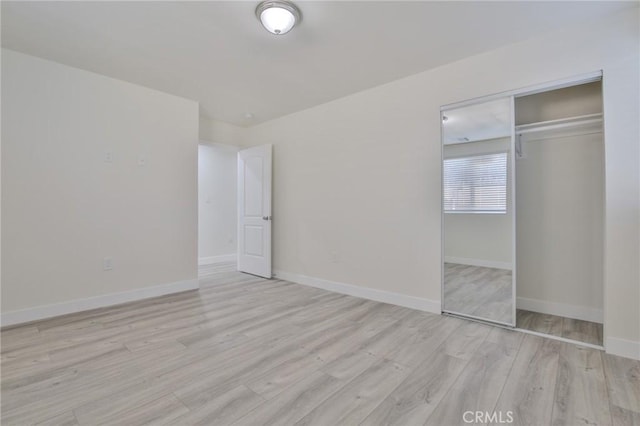 unfurnished bedroom featuring baseboards, a closet, and wood finished floors