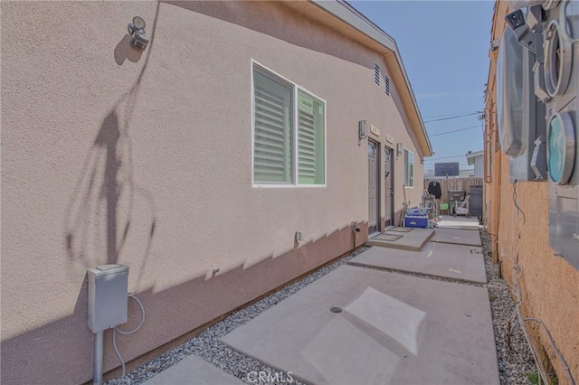view of property exterior featuring fence, stucco siding, and a patio area