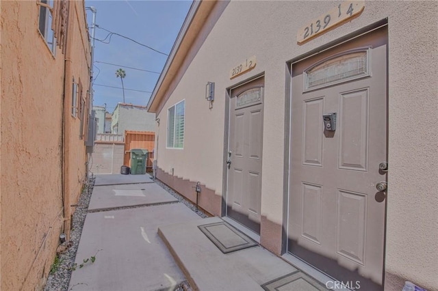 property entrance with stucco siding and fence