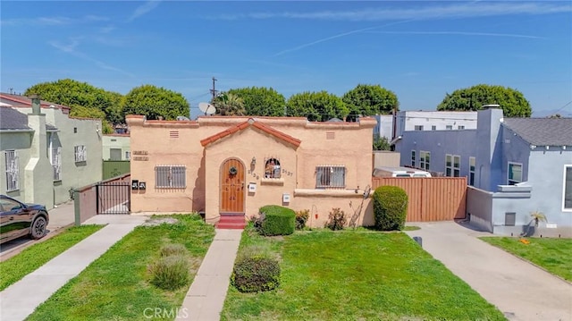 mediterranean / spanish-style home featuring stucco siding, a gate, fence, and a front yard