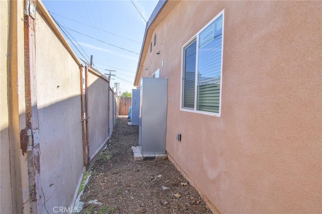 view of side of home with stucco siding and fence