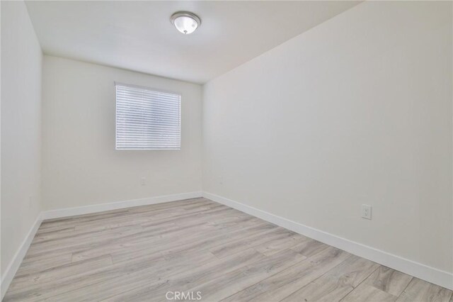 empty room featuring baseboards and light wood-style flooring