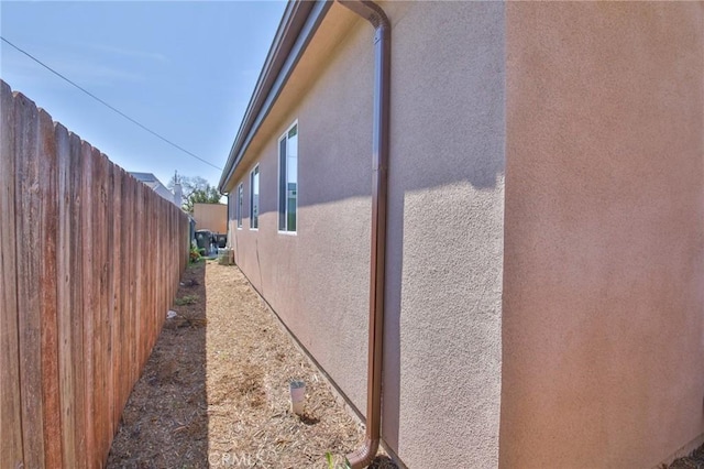 view of side of home featuring fence and stucco siding