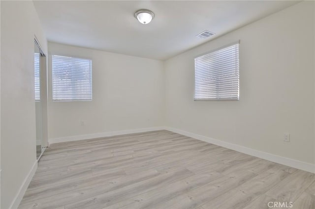 spare room with baseboards, visible vents, and light wood-type flooring